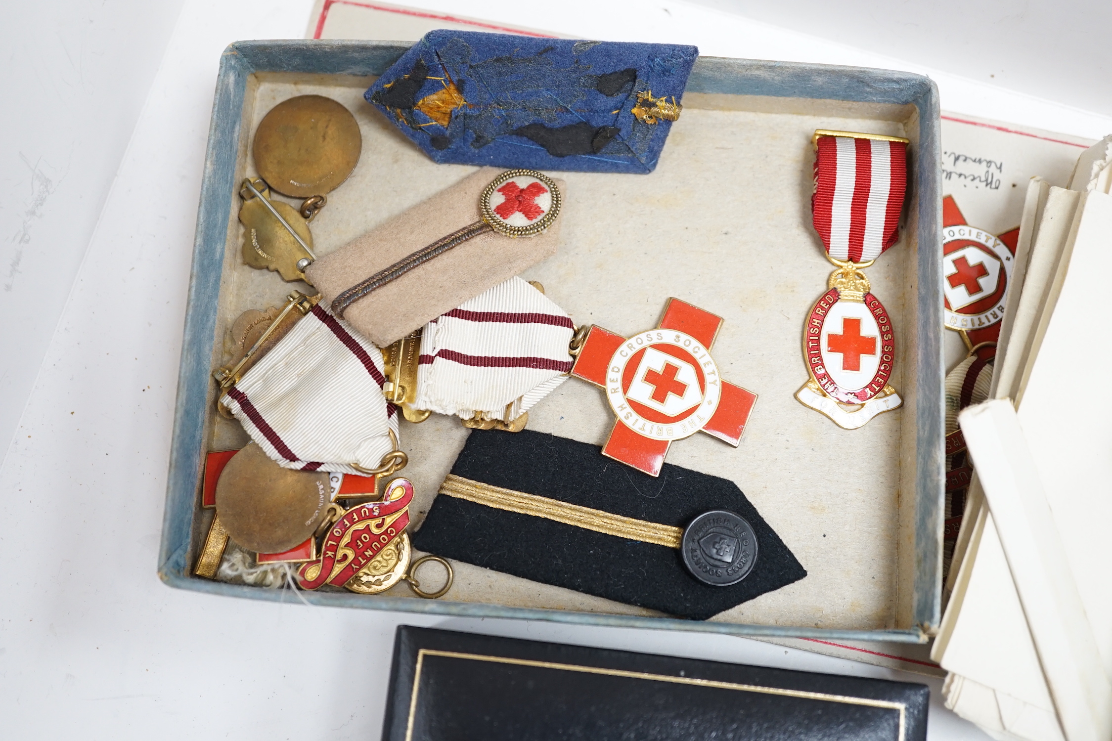 A collection of British Red Cross, medals, badges and memorabilia including a brass plaque, commemorating an auxiliary hospital during the Great War, proficiency, medals, long, service, medals, metal boxes, and some pape